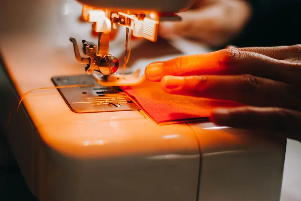 Máquina de coser trabajando sobre una tela roja